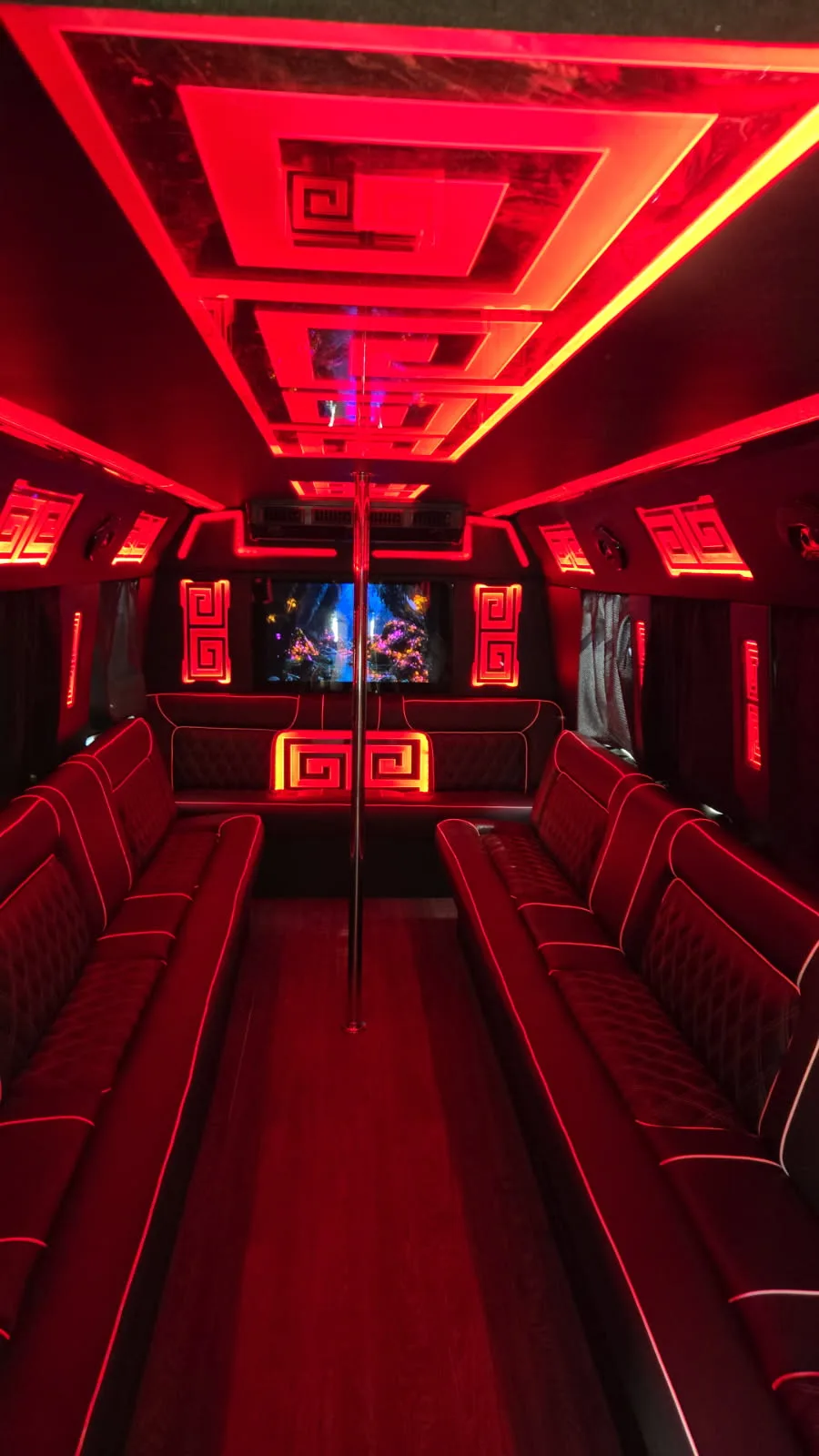 Party bus interior glowing red with dance pole