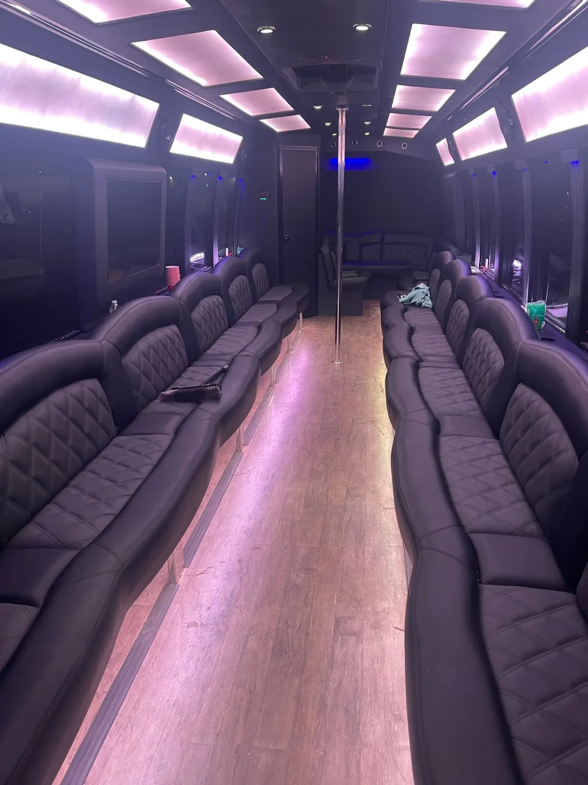 Large party bus interior with pole and soft white lighting