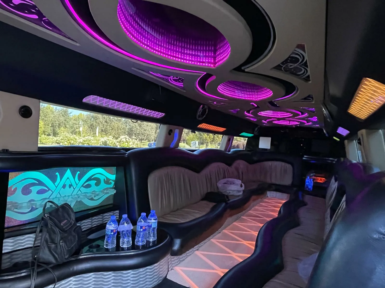 Stretch limo interior with purple ceiling lights and TV screens