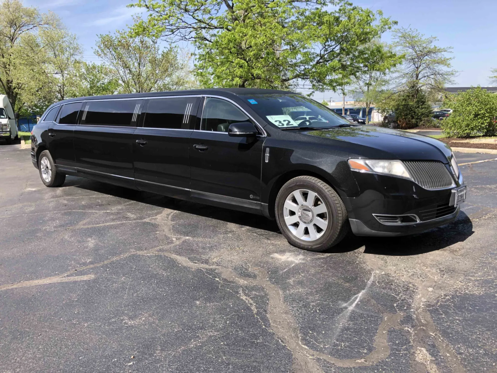 Black Lincoln MKT stretch limousine parked under trees