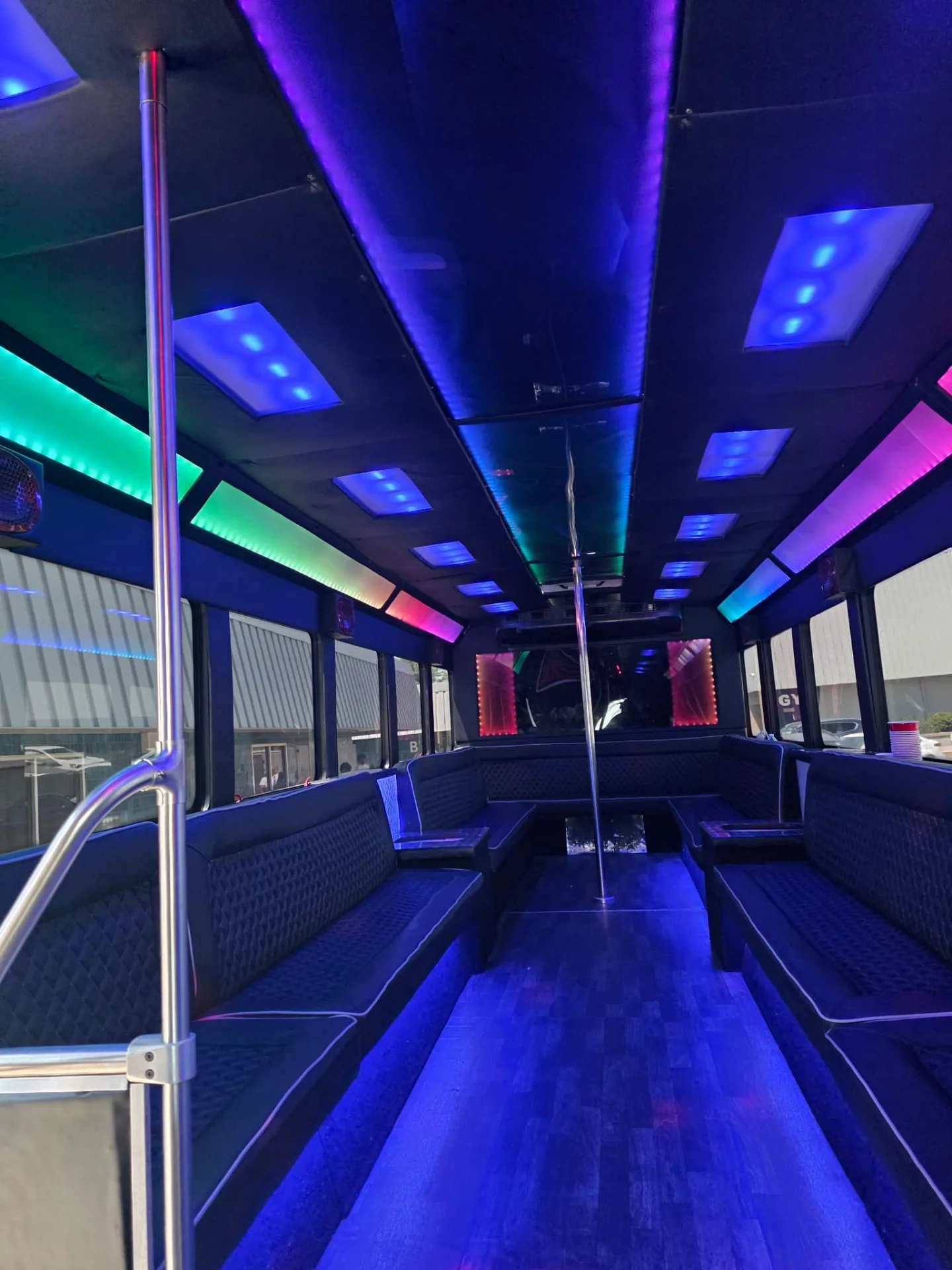 Party bus interior with rainbow ceiling lights and pole