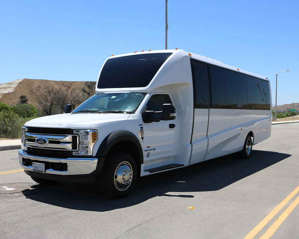 White 24-passenger party bus on the road