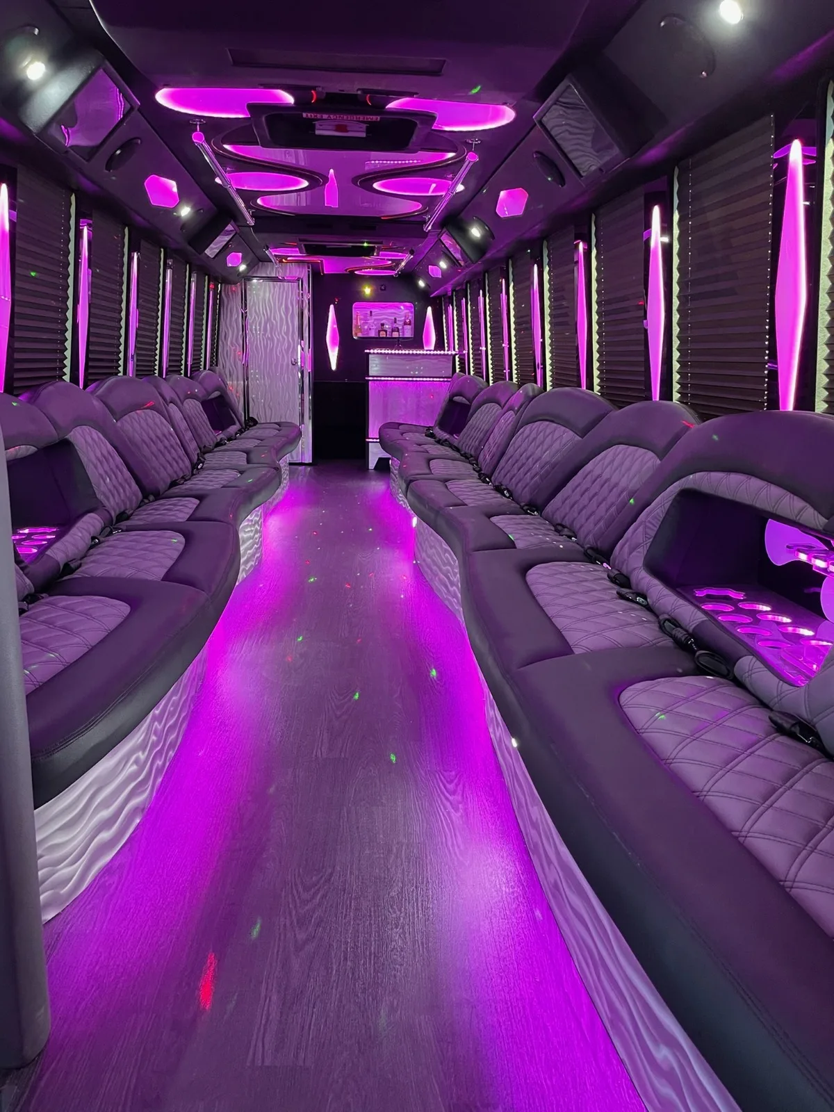 Party bus interior rows of quilted seats in purple light