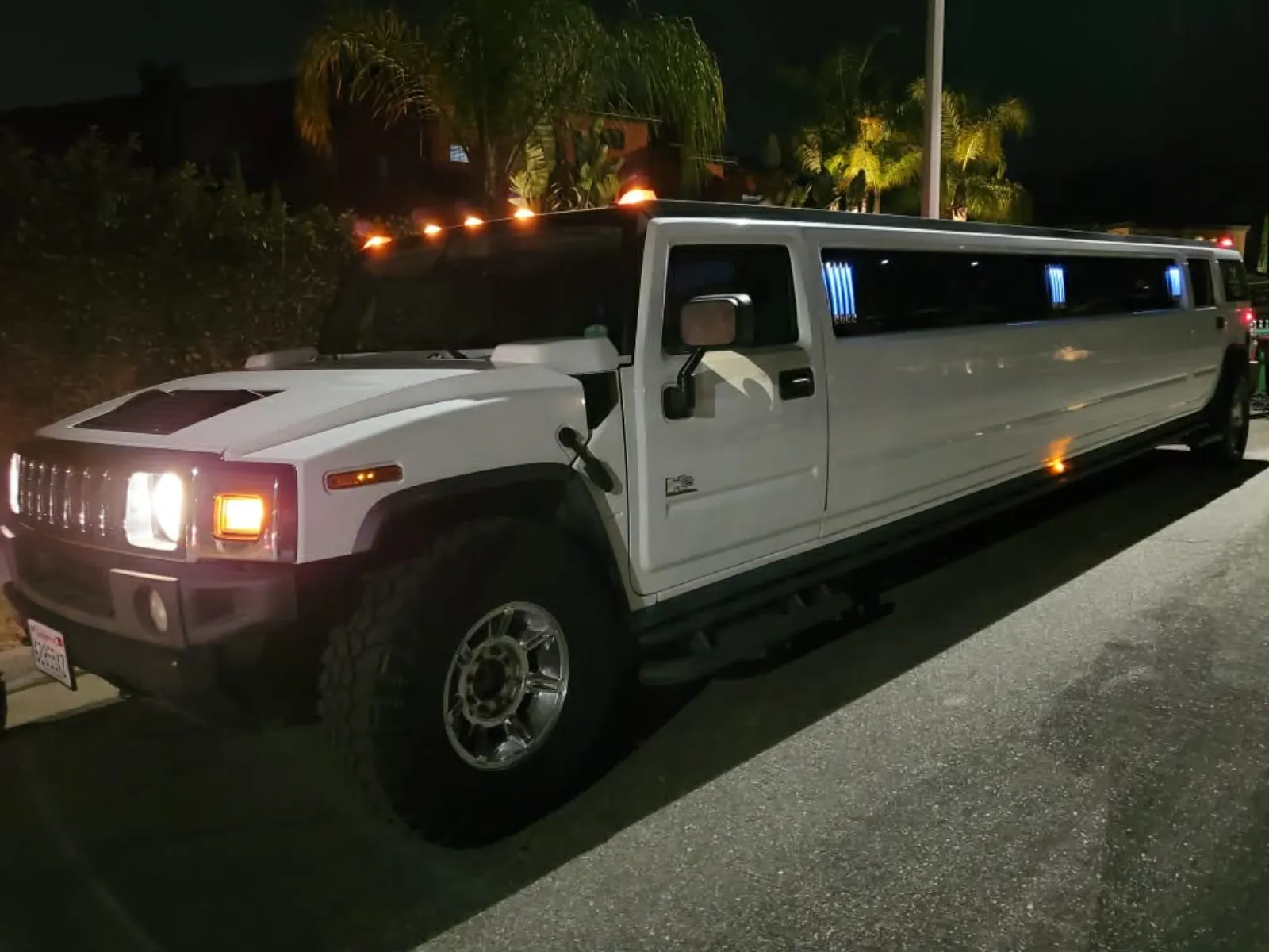 White Hummer stretch limousine lit up at night